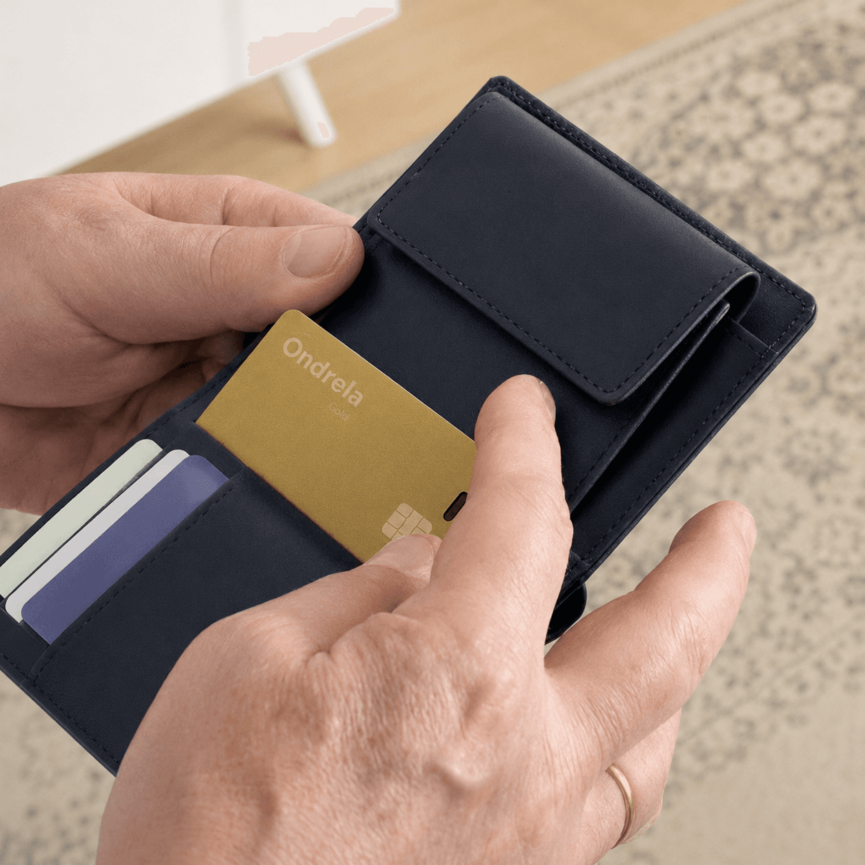 Hands placing an Ondrela Gold tracking card inside a dark wallet
